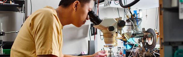 азиатский техник, работающий с микроскопом на рабочем месте в ремонтной мастерской, малый бизнес, баннер - Фото, изображение