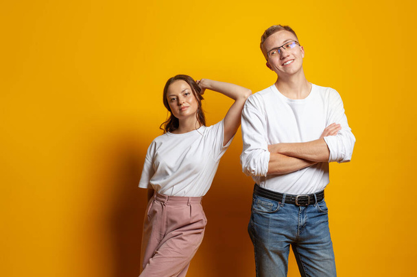 Portret van schattig succesvol paar jonge man en vrouw staan op gele achtergrond - Foto, afbeelding
