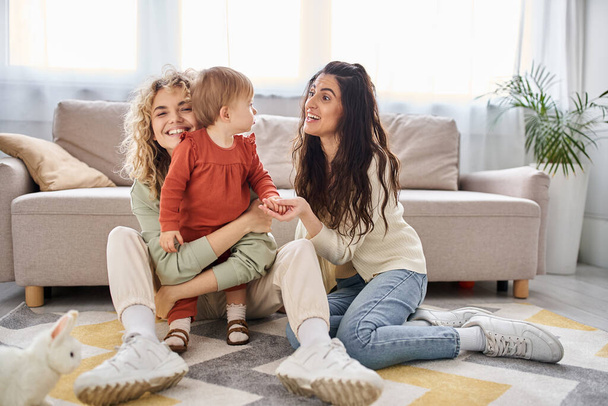 attractive joyous lgbt couple having great time together with their daughter at home, family concept - Photo, Image