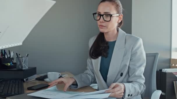 Střední sklon pomalý záběr běru bělošky žena režisérka v brýlích listování v polovině čtvrtletí zprávy a pak odpověď na otázku černých zaměstnanců v kanceláři - Záběry, video
