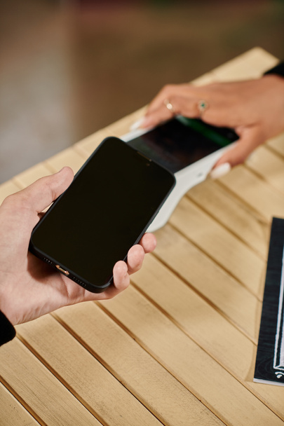 Оплата смартфона, обрезанный вид человека, держащего свой смартфон рядом с кард-ридером в веганском кафе - Фото, изображение