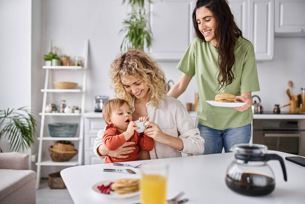 happy beautiful lgbt couple in homewear having great time with their daughter at breakfast, family - Photo, Image