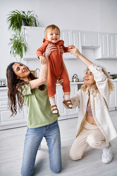 charmante glücklich lgbt Paar aktiv spielen mit ihren niedlichen Kleinkind Tochter, moderne Elternschaft - Foto, Bild