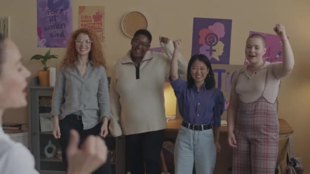 Медиум сняла группу феминистских активистов с женщиной-лидером в голове, поднимающей кулаки в знак протеста перед тем, как пойти на демонстрационную встречу вместе и бороться за гендерное равенство и права женщин - Кадры, видео