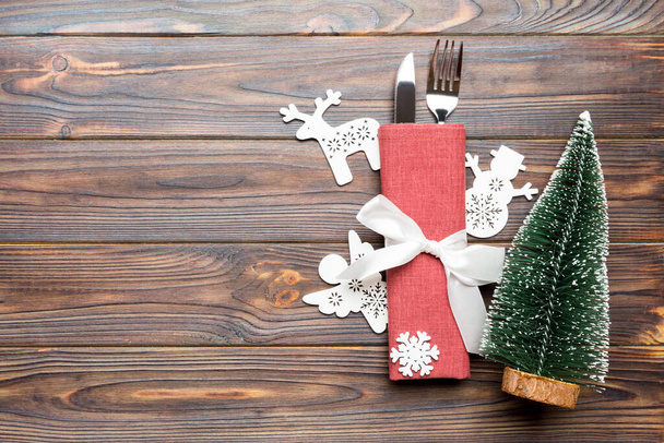 Vista superior de tenedor y cuchillo atado con cinta en servilleta sobre fondo de madera. Decoraciones de Navidad y árbol de Año Nuevo. Feliz concepto de vacaciones con espacio vacío para su diseño. - Foto, imagen