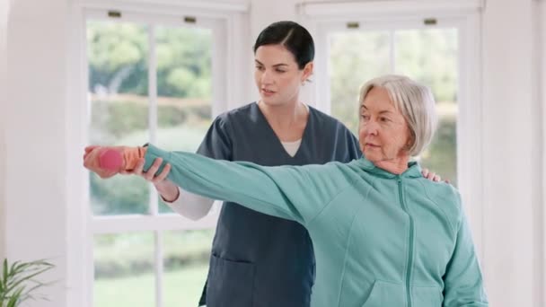 Nő, nővér és idős beteg súlyzóval fizioterápiában, fitneszben vagy testmozgásban idős korban otthon. Női személy, terapeuta vagy orvos segít az ügyfélnek nyújtásban, terápiában vagy súlyemelésben a házban. - Felvétel, videó