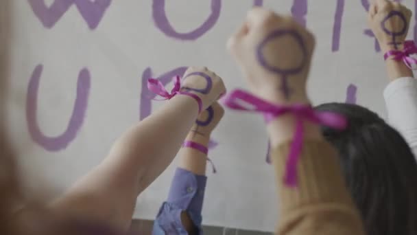 Медленно неузнаваемые женщины кладут свои кулаки с фиолетовыми феминистскими символами и лентами на запястьях в воздух, борясь за гендерное равенство вместе - Кадры, видео