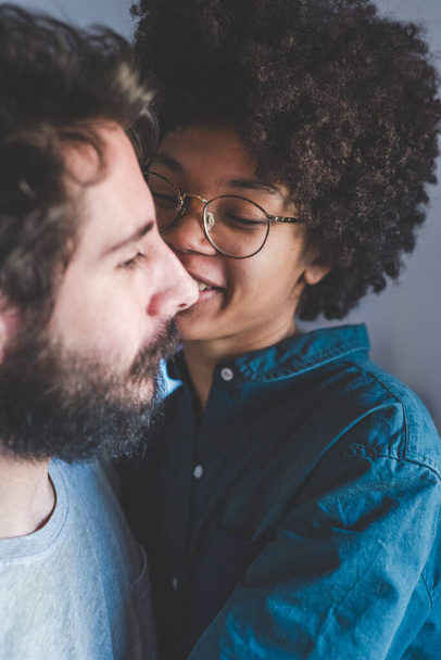 Joven pareja multiétnica abrazándose sonriendo juntos en casa  - Foto, Imagen