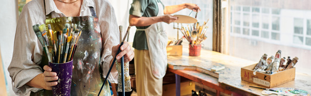 vista recortada de artistas femeninas maduras eligiendo pinceles en taller de artesanía, pancarta horizontal - Foto, Imagen