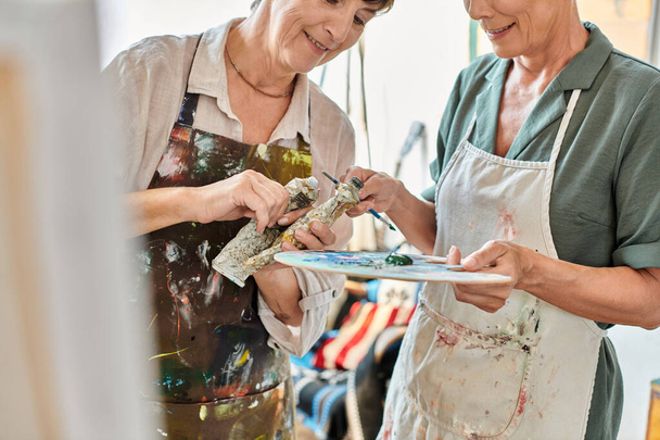 sorrindo mulheres maduras misturando tintas na paleta de cores durante a pintura master class no estúdio de arte - Foto, Imagem