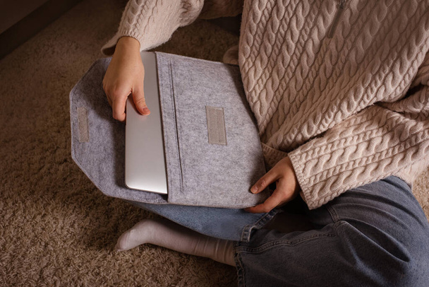 koperta z filcu do ochrony laptopa. kobieta trzyma się za ręce siedząc w domu na dywanie - Zdjęcie, obraz