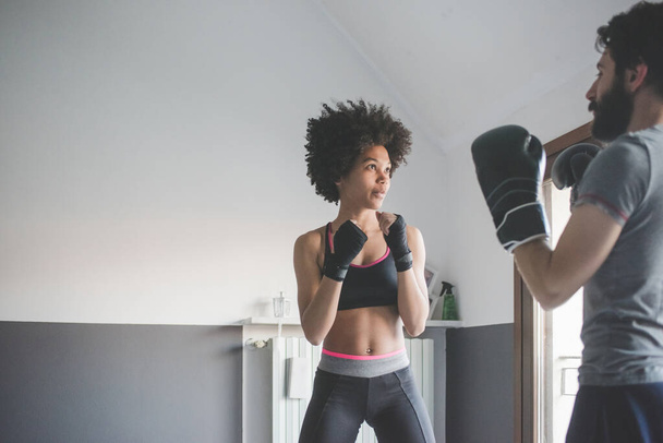 Nuori monikansallinen nainen kotona harjoittelu valmentaja tekee nyrkkeily liikunta   - Valokuva, kuva