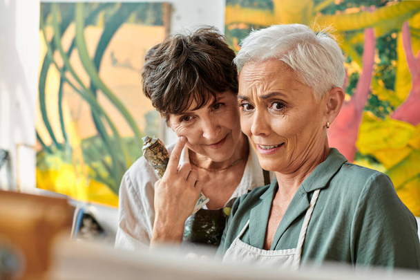 positief en duur volwassen vrouwen kijken naar ezel tijdens schilderkunst masterclass in kunst workshop - Foto, afbeelding