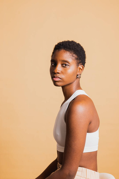 Portrét vážné mladé krásné africké Američanky stojící na hnědém pozadí a dívající se do kamery. Mladá žena se dívá do kamery. - Fotografie, Obrázek