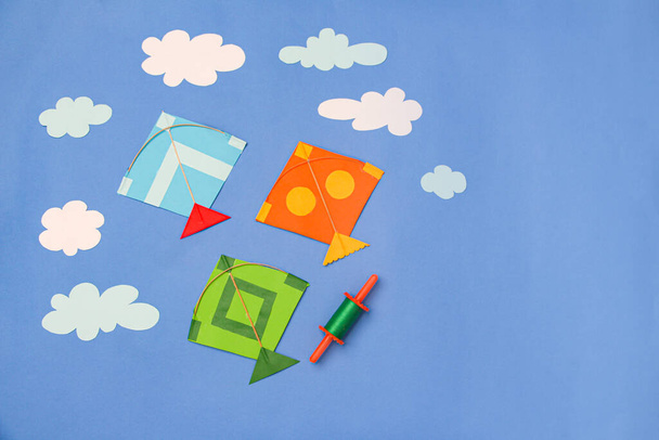 Паперові вироби барвисті паперові повітряні змії та хмари на синьому фоні  - Фото, зображення