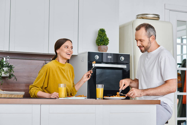 現代のキッチンでおいしい朝食の間に話している陽気な子供のないカップル,穏やかさと団結 - 写真・画像
