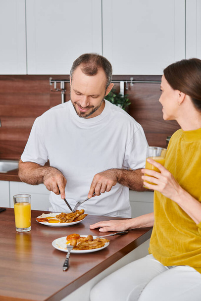 szczęśliwy człowiek o pyszne śniadanie w pobliżu żony w nowoczesnej kuchni, rano para wolna od dzieci - Zdjęcie, obraz
