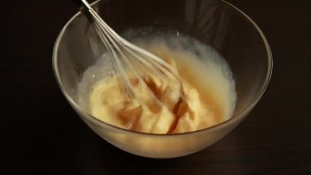 Flüssige Zutaten für Pfannkuchen mit einem Schneebesen mischen. Draufsicht auf den Küchentisch. Kochen in der Küche - Filmmaterial, Video