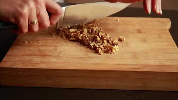 les mains de la femme ferment les noix de coupe sur une planche en bois - Séquence, vidéo