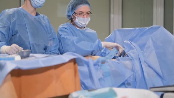 Een arts en een assistent voeren chirurgische ingreep uit voor spataderen. - Video