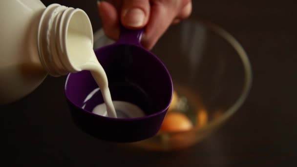 Крупным планом руки наливают молоко в измерительную чашку, чтобы сделать печенье. - Кадры, видео