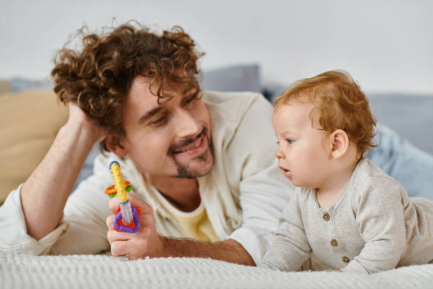 onnellinen mies osoittaa värikäs helistin pikkulapsi poika makuuhuoneessa, side isän ja pojan - Valokuva, kuva
