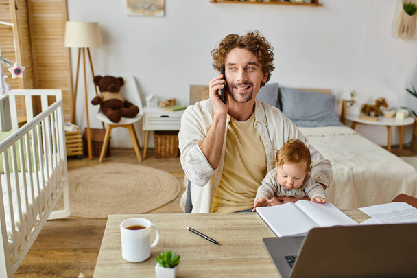 Çocuk kucağında mutlu bir adam akıllı telefonla konuşurken ve evde çalışırken, iş hayatı dengesi - Fotoğraf, Görsel