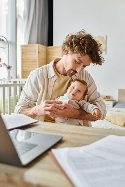 自宅で働いている間,ミルクと授乳中の幼児の息子と赤ん坊のボトルを持っている父親の世話 - 写真・画像