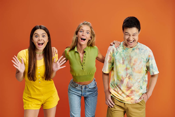 веселі мультикультурні підлітки в повсякденних яскравих вбраннях розважаються і дивляться на камеру, день дружби - Фото, зображення