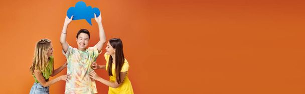 jolly diverse teens posing with blue thought bubble on orange backdrop, friendship day, banner - Photo, Image