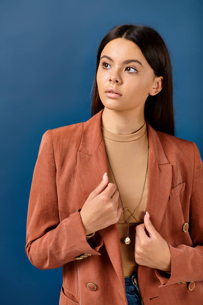 adolescente menina na moda em blazer marrom elegante posando no fundo azul e olhando para longe - Foto, Imagem