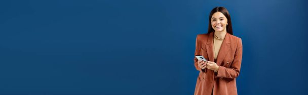vrolijk stijlvol tienermeisje in elegante blazer met smartphone en glimlach op de camera, banner - Foto, afbeelding