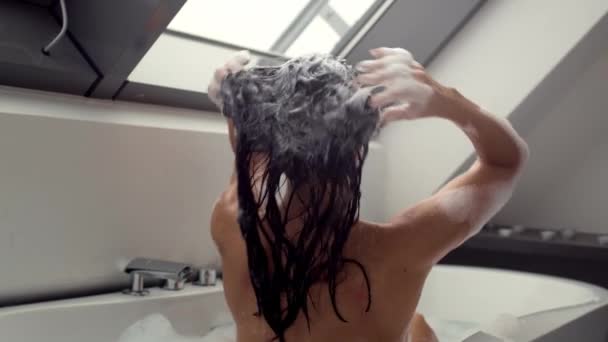 Lenyűgöző 4K videó felvétel rögzíti gyönyörű nő fürdés közben, aprólékosan mossa a haját habos samponnal, lassított felvétel. A jelenet a személyes gondoskodás és a szépségápolás intim pillanatait mutatja be - Felvétel, videó