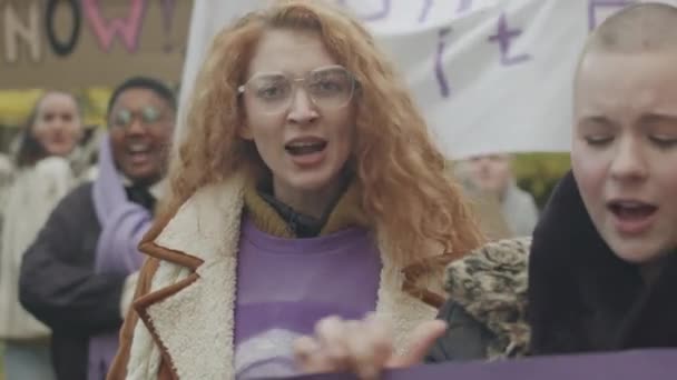 Талия толпы многоэтнических молодых феминисток с плакатами и баннерами в руках, борющихся за гендерное равенство и права женщин на улице на забастовке - Кадры, видео