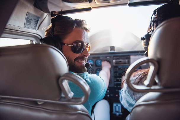Вид сзади изнутри самолета, пара в авиационных наушниках готова к полету
 - Фото, изображение