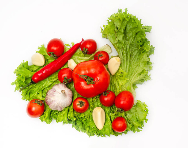 Meng van verse groenten - peper, knoflook, tomaten en groene saladebladeren. Witte achtergrond, geïsoleerd - Foto, afbeelding