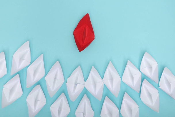 Leadership koncept s červeným papírem loď vedoucí mezi skupinou bílých lodí na bílém pozadí - Fotografie, Obrázek