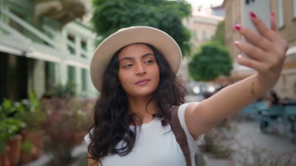 Счастливая улыбающаяся индийская арабская этническая женщина девушка студентка туристический путешественник влиятельный делает селфи фото мобильный телефон камеры города за пределами путешествия видео поток социальных медиа отпуск - Кадры, видео