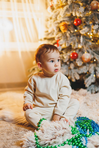 Een jongetje, 1 jaar oud, siert de kerstboom. Nieuwjaar. Kerstboom. - Foto, afbeelding