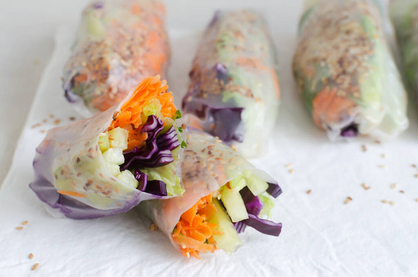 Vegetarian vietnamese spring rolls with carrot, cucumber, red cabbage, cilantro, sesame and rice noodle on a white board. veggie dish. Vegan food. Horizontal orientation. Selective focus - Photo, Image