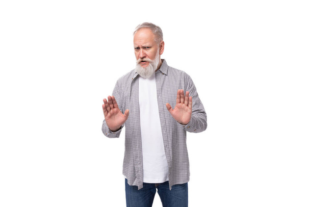 schöner Rentner mit Bart und dickem Schnurrbart ist mit Hemd und Jeans bekleidet. - Foto, Bild