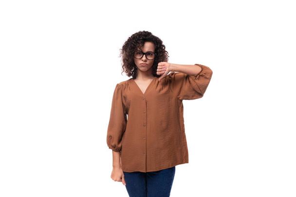 молода кучерява брюнетка, одягнена в коричневу блузку, показує жест розбіжностей. - Фото, зображення