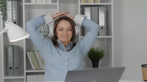 Egy nő egy asztalnál egy laptopnál hátradől egy székben, mosollyal az arcán és álmodozó tekintettel. Munka, tanulás és pihenés egy kényelmes munkahelyen. Kiváló minőségű 4k felvételek - Felvétel, videó