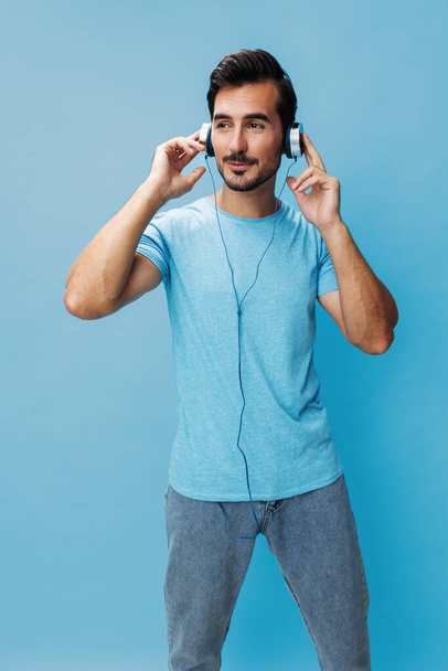 Чоловік з радістю співає студійний спосіб життя онлайн веселі емоції хлопець говорить портретну копію музики вирізаний фон слухати синій насолоджуйтесь футболкою навушники щасливий простір - Фото, зображення