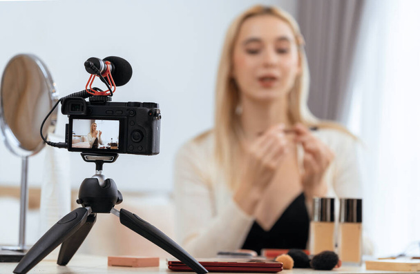 Blurred young woman making beauty and cosmetic tutorial video content for social media. Focused camera screen with beauty influencer showing how to apply beauty care to audience or followers. Blithe - Photo, Image