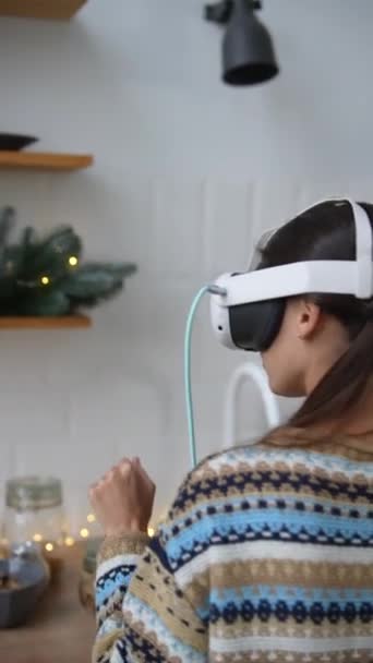 Une jeune femme élégante cuisine dans la cuisine avec un casque de réalité virtuelle. Noëlmastime. Images 4k de haute qualité - Séquence, vidéo