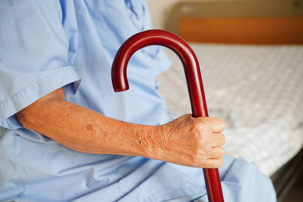 Жінка похилого віку в Азії терпелива, тримаючи палицю в зморшкуватому руці в лікарні.. - Фото, зображення