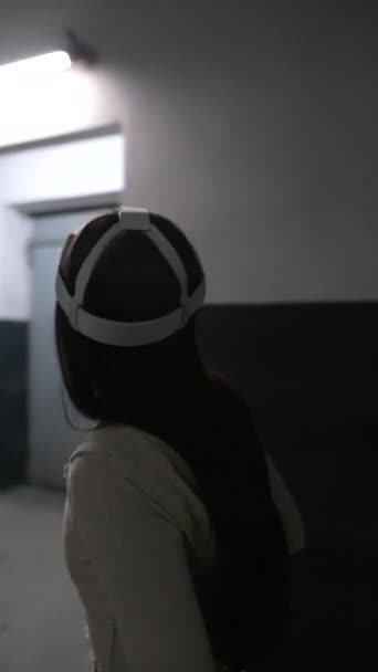 Una bella donna in abbigliamento sportivo cammina lungo il corridoio indossando un auricolare di realtà virtuale. Filmati 4k di alta qualità - Filmati, video