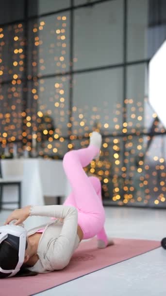 Wearing a virtual reality headset, she engages in body warm-up exercises on a pink yoga mat. High quality 4k footage - Footage, Video
