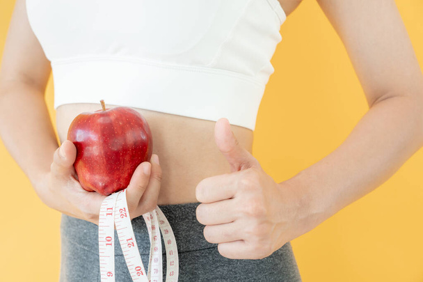 szczupłe ciało azjatyckie kobiety wybrać zdrową żywność, diety kobiet wybrać czerwone jabłko do diety. Dobre zdrowe jedzenie. utrata masy ciała, równowaga, kontrola, zmniejszenie tłuszczu, niskie kalorie, rutyny, ćwiczenia, kształt ciała. - Zdjęcie, obraz